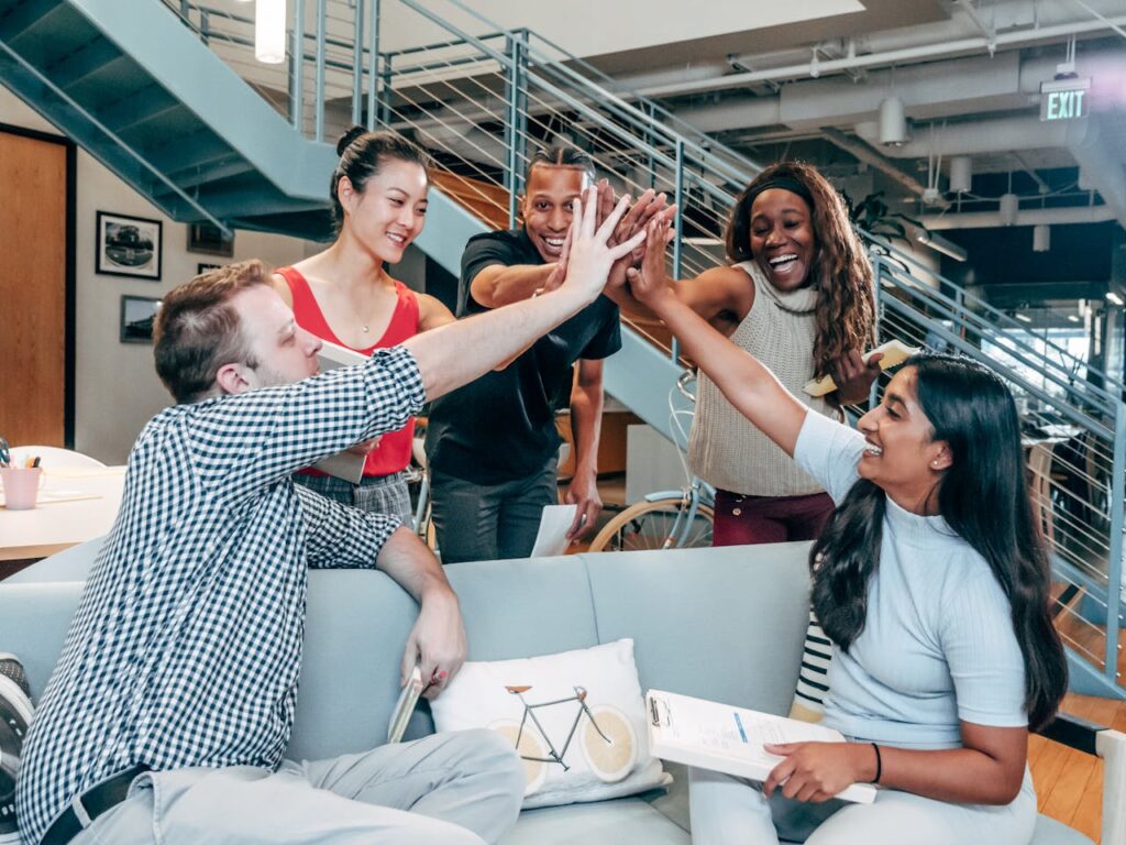 pexels-photo-7688174 A multicultural office team high-fiving and celebrating a successful collaboration.